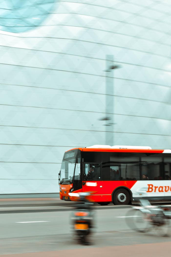 Dynamic cityscape with a red bus in motion, set against a modern building facade.