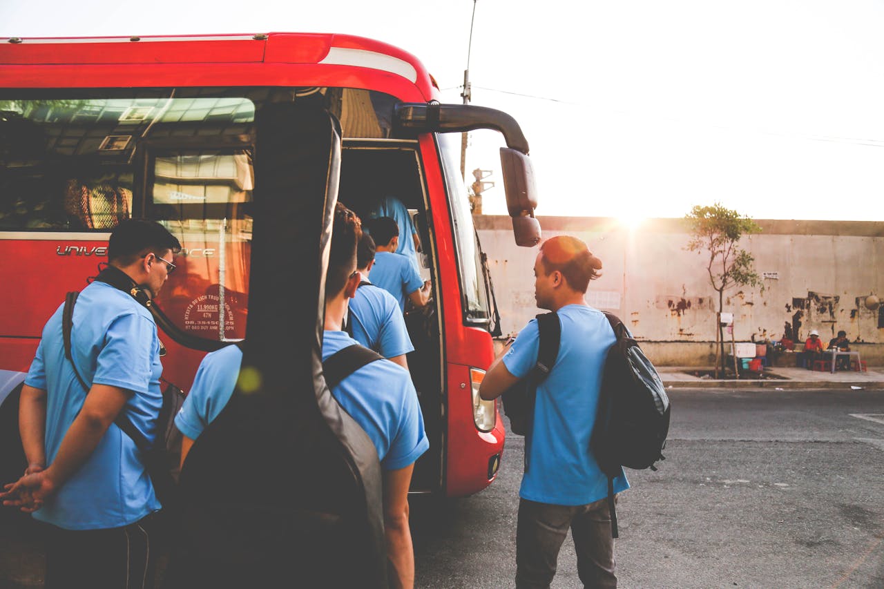 services-01 Musicians boarding a red bus in Tân Bình, Hồ Chí Minh City during sunrise. A lively street scene.